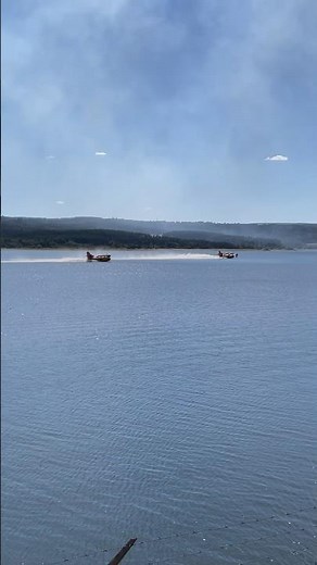 🔥🌊 Two Canadair water bombers scoop water from a lake to extinguish a raging forest fire