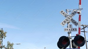 Level crossing warning signal in USA. Crossbuck notice and red traffic light on rail road intersection in California. Railway transportation safety symbol. Caution sign about hazard and train track.