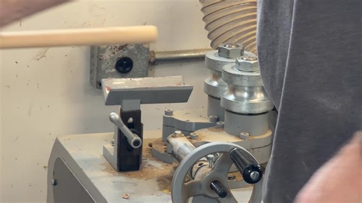 Years ago, we'd square up stock with jointer and planer, cut into an octagon cross section, then a 16 sided shape and finally hand sand it to make a round staff. An intensely labor intensive process with significant variability; it was an unsustainably difficult thing to do. Now we use a custom built machine that makes perfect cylinders for bo, jo, self defense canes, and hiking sticks. Here, master craftsman Benny Danaher runs the round rod machine. | Kingfisher WoodWorks LLC