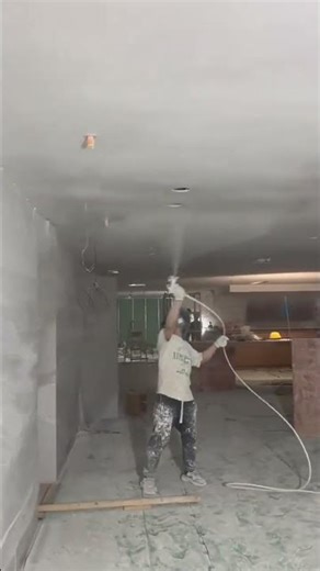 spraying white paint on ceiling using airless spray machine in building renovation