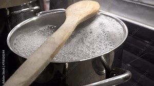 Boiling pasta water on an induction stovetop and a wooden spoon to prevent boilover.