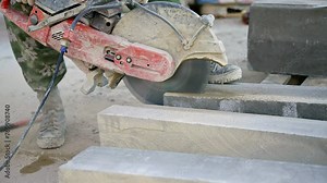 A man is using a circular saw to cut concrete blocks at a construction site