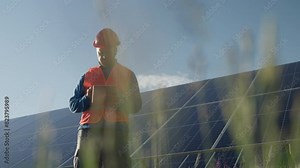 Young Solar Engineer Using the Tablet in front of the photovoltaic solar panels on a Sunny Day. Concept of Sustainable Green Energy, Electric Power, Ecology, Inspection, Maintenance Check