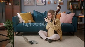 Man playing pipa, Chinese folk string instrument. Young male blogger studying how to play acoustic musical instruments using online video lesson on laptop at home during coronavirus lockdown.