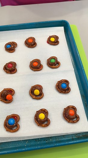 Yummy chocolate pretzel snack Olivia uses pretzels, hershey kisses and M&Ms to make an easy snack (Put the kisses on the pretzels and place in the oven at 300 degrees until melted. While warm, place the m&ms on top) This original video was produced by Network Media LLC and Olivia | Jacky and Olivia’s Kitchen