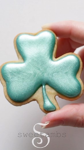 I used @roxyandrich luster dust in emerald green to add shine to my shamrock cookies ☘️ Add a few drops of vodka, grain alcohol, or any flavor extract to create luster paint! #shamrockcookies #saintpatricksdaycookies #stpatricksdaycookies #royalicing #icingcookies #decoratedcookies #cookiedecorating | SweetAmbs