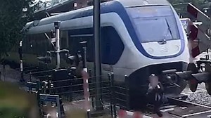 Train narrowly misses woman running over crossing
