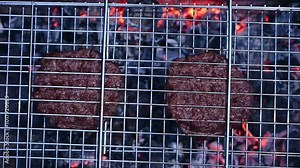 Grilling hamburger patties on a charcoal grill creates a delicious meal for an outdoor summer evening party