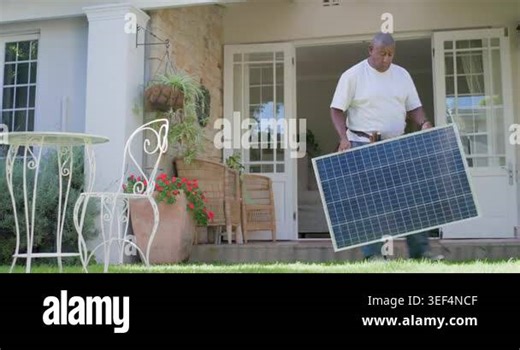 African American tech with toolbelt carrying solar panel to porch, owner checking phone confirming. Photovoltaic, module, installation, contractor, residential, suburban, veranda Stock Video Footage - Alamy