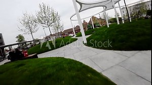 This video showcases a modern city park with a unique and contemporary landscape design. The park features several grassy hills, curved concrete pathways, and strategically placed seating areas