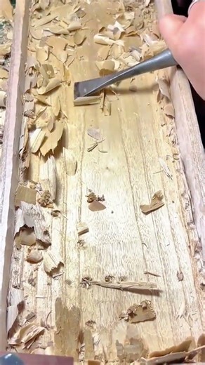 chiseling wood surface with a sharp manual tool to create flat base for handmade wooden container