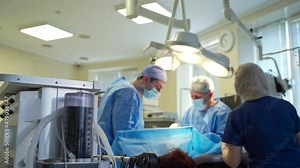 Working pumping heart lung machine during the operation. Two male doctors taking care of a patient at the backdrop in blur.
