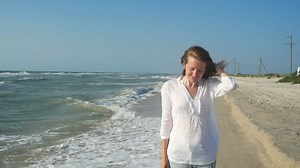 Woman walking along the seashore - Free Stock Video