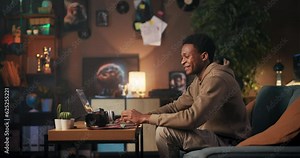 Music Producer: An African American man creating music on his computer while wearing headphones, smiling, and dancing to the beats he produces.