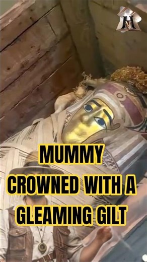 Amummy crowned with a gleaming gilt mask and floral garlands.