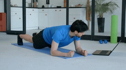 clip-4032639605-sporty-fit-man-activewear-watching-video-tutorial