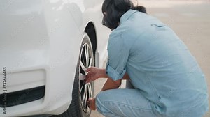 Woman checks a flat tire puncture while waiting for a tire and car service technician to call to help.