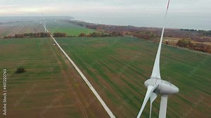 Spinning Wind Turbines On Beautiful Sunset Spring Landscape. Green Ecological Power Energy Generation. Wind Turbines Farm Eco Field. Sunrise Above Windmills On Field. Aerial View. Energy Production.
