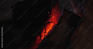 Extreme close-up of a burning hearth. Wooden logs smolder brightly in the fire. Beautiful background with copy space. Bright flames of fire over black background, slow motion 50 fps 4k