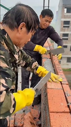 These two workers build a strong wall on the upper floor with teamwork, balance, and skilled effort