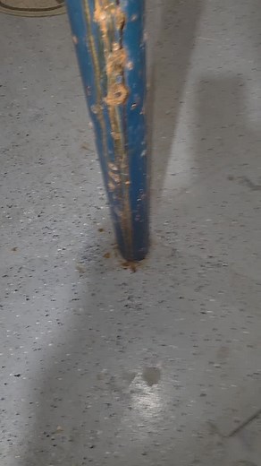 This isn’t surface rust — groundwater is wicking up from the slab and rotting this post from the inside out. They painted it blue like makeup on a corpse, hoping nobody would notice the steel turning to oatmeal underneath. When a support post starts drinking groundwater, the inside doesn’t bend… it just gives up. And at this stage, this thing is whispering, ‘I’m tired, boss… I don’t wanna hold this house up no more.’ If your home depends on a hollow, water-logged metal tube, it’s time to untie t