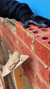 A builder is installing red bricks on a building