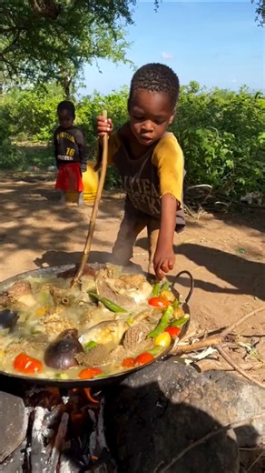 This little child is cooking in the forest in a primitive way.