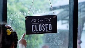 Download A closed sign hanging on the front door of the restaurant swaying on a rainy day for free