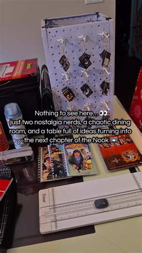 Please ignore the Christmas chair covers… the cat chose chaos and destroyed the others 😭🎄 Honestly though, this is real life while we build the next chapter of Nostalgia Nook. A busy dining room, thrifted finds, stacks of VHS covers, and two nostalgia collectors turning big ideas into handmade pieces we can share with fellow physical media lovers 📼✨ Between upcycled projects, mini VHS keychains, NookBooks, and late-night creation sessions, this is the behind-the-scenes of growing a small nost