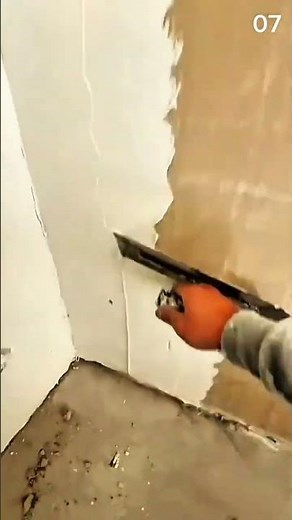 Scooping white plaster from bucket using metal trowel