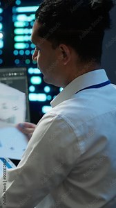 Vertical video System administrator in data center maintaining accurate paperwork of hardware, generating reports. IT expert in high tech server farm doing workplace disaster recovery planning, camera