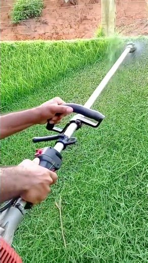 A person is spraying liquid fertilizer onto a bright green lawn