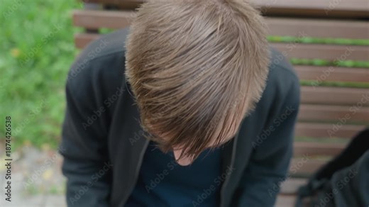 man staring into camera atop park bench wet hair intense gaze direct confrontation urban grit daylight closeup raw expression backpack beside him grass backdrop roles skater, street poet, actor,
