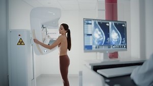 Computer Screen in Hospital Radiology Room: Beautiful Multiethnic Adult Woman Standing Topless Undergoing Mammography Screening Procedure. Screen Showing the Mammogram Scans of Dense Breast Tissues.