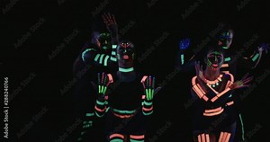 Studio, slow motion, a group of four neon-painted dancers dancing