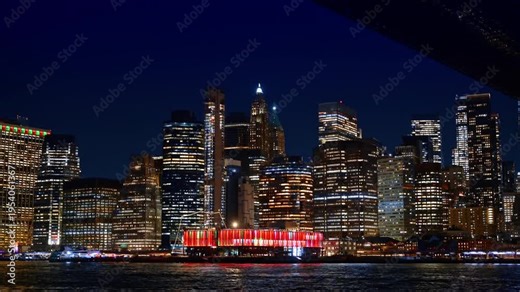 Red illumination of Pier 17 bar in New York, USA. View on the city from another side of the river at night.