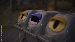 4k front view grey trash can, yellow and blue top cap at local park, recycling routine, littering, rubbish dispose, environment conservation concept, plastic recycle, trash reuse, social problem