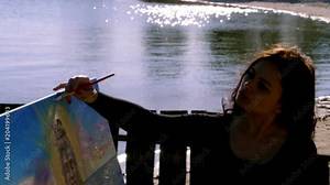 summer, near river, on the beach. at sunrise, a beautiful woman artist holds a brush in her hand, draws a picture. she paints on canvas the god Shiva.