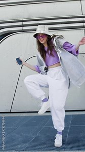 Cool young woman dancing with mobile. Urban futuristic background. Model posing in 4K, UHD