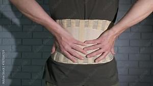 Elastic bandage during back pain. A male show her elastic bandage on his back during pain.