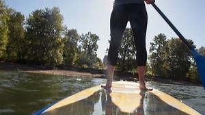 Handheld shot of woman paddleboarding in river