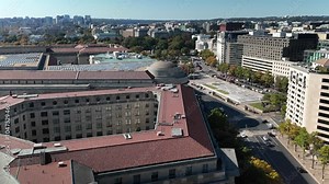 Aerial view of Washington DC showcasing White House, EPA, buildings, a large plaza, trees, and streets with cars. The image captures a blend of urban and natural elements.