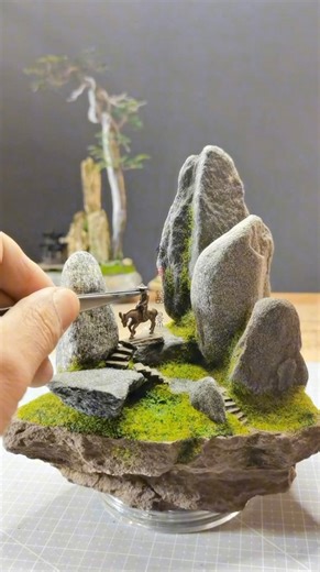 Artists Universum 🖌️ on Instagram: "Golden Stone Landscape Art is a Chinese miniature artist who creates detailed landscapes using stones, moss-like greenery, and natural textures. He carefully positions each rock to form mountains and terrain, then adds adhesive and fine green materials that mimic grass and vegetation, gradually bringing each scene to life. Artist: mj15006597 / 金石造景 on Douyin #art #artist #miniature"