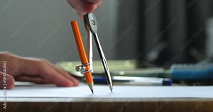 Using compass with pencil to draw a drawing close-up. Architecture designer draws circle with compass, professional engineer working, interior creator making project, drafting building.