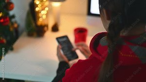 Over shoulder view of young woman reading message on mobile phone during winter holidays