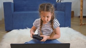 Teenage girl playing with remote control joystick while having fun at home. A happy child interacts with technology while playing at home with modern toys. Gamer girl with remote control joystick.