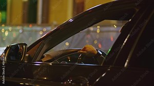 Man's hand behind wheel of car. Clip. View from car window with man's hand on steering wheel. Rich man driving car in night city