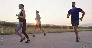 Multiethnic group of athletes running together on a panoramic countryside road. Diverse Team of joggers on morning training.
