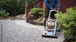 Closeup of the vibratory plate compactor as it settles the dirt and gravel at the start of the hardscaping process.