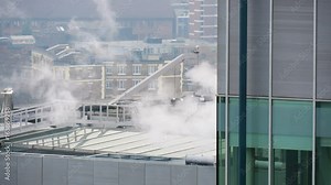 Steam coming from buildings and dissipating in the winter air.